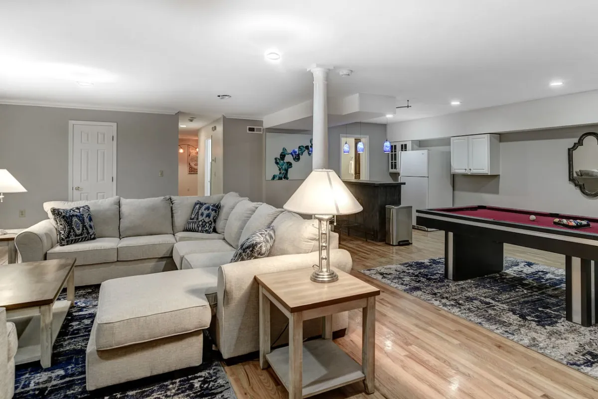 This interior image showcases a cozy area with a sofa, pool table, and a lamp. The space has an inviting ambience perfect for gatherings, with the pool table as a focal point for game nights and plush seating providing comfort for relaxation and conversation.