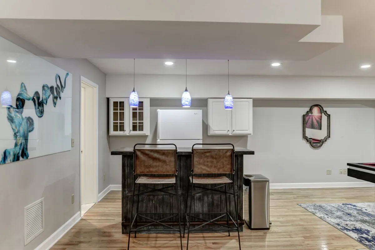 This bar area features stools, pendant lighting, and decorative artwork. The space is designed for socializing and relaxed conversations, ideal for a group gathering after a day outside.
