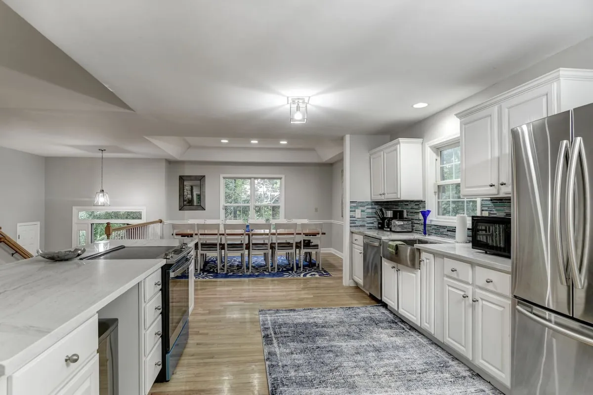 This image showcases a spacious, welcoming kitchen with a prominent island, stainless steel appliances, and a large dining table—ideal for group gatherings and celebratory meals. The layout suggests room for both meal preparation and socializing, echoing the spirit of shared experiences.