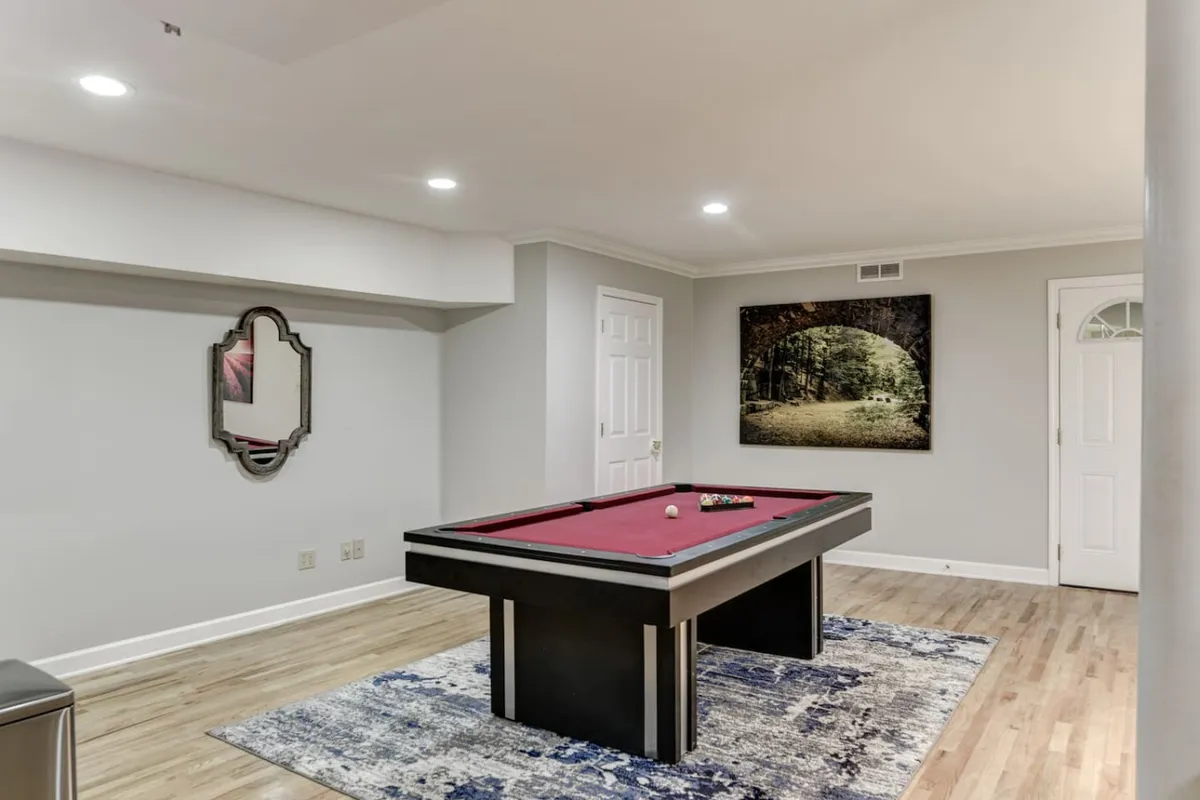 This interior image centers on a pool table, with a large mirror and landscape artwork on the walls. The space is designed for leisure, socialization, and friendly competition, embodying the spirit of game nights and shared memories.