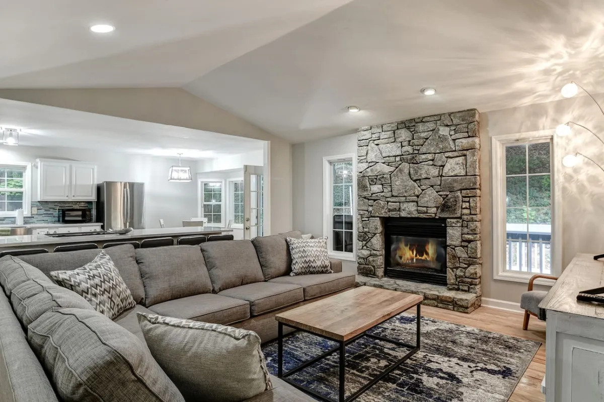 A cozy living room focused on a stone fireplace, with a comfortable sofa and coffee table creating a welcoming space for relaxation and socializing. The ambiance is warm and inviting, perfect for recounting the day's adventures with friends or family.
